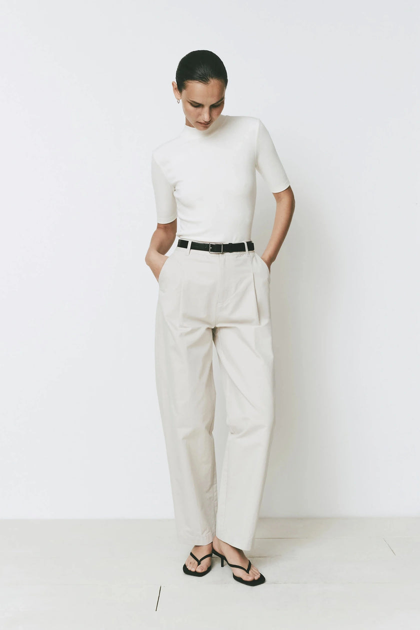 Cream wide-leg Parc Pant with tailored fit, paired with a white top and a black belt. Sophisticated design.