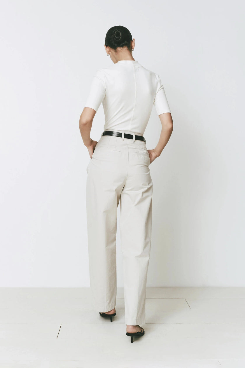 Cream wide-leg Parc Pants with tailored fit, white top, black belt, and sandals. Sophisticated look.