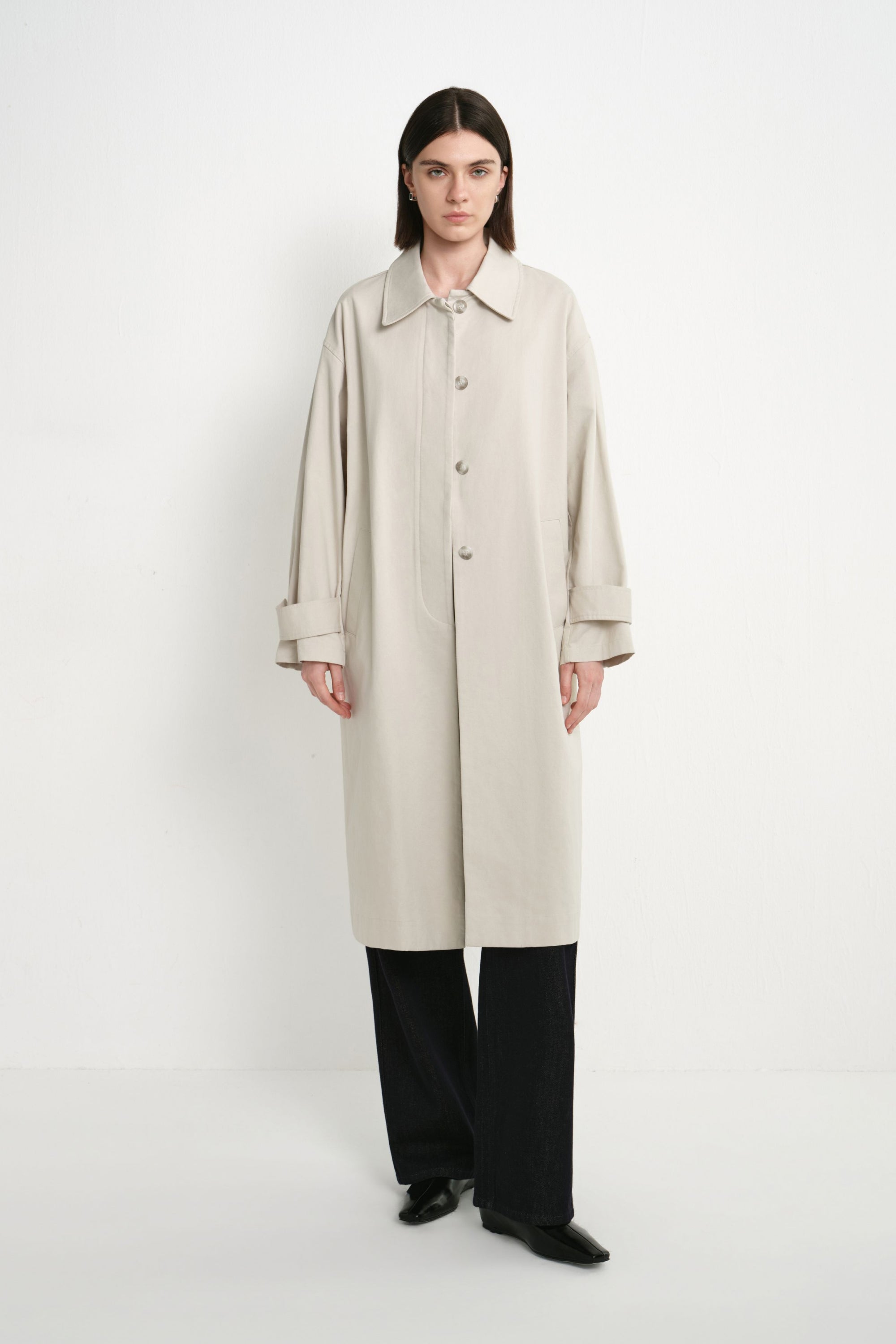 A model wearing the Rue Sophie Roche Oversized Jacket in cement with a pointed collar, button-front closure, adjustable cuff tabs, and an oversized straight silhouette, front view.