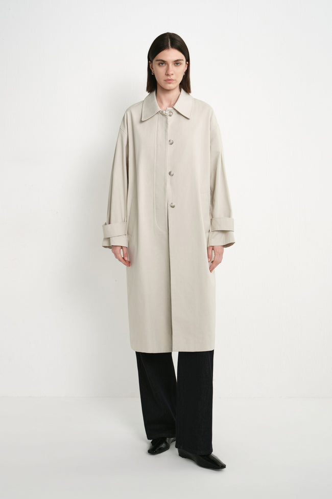 A model wearing the Rue Sophie Roche Oversized Jacket in cement with a pointed collar, button-front closure, adjustable cuff tabs, and an oversized straight silhouette, front view.
