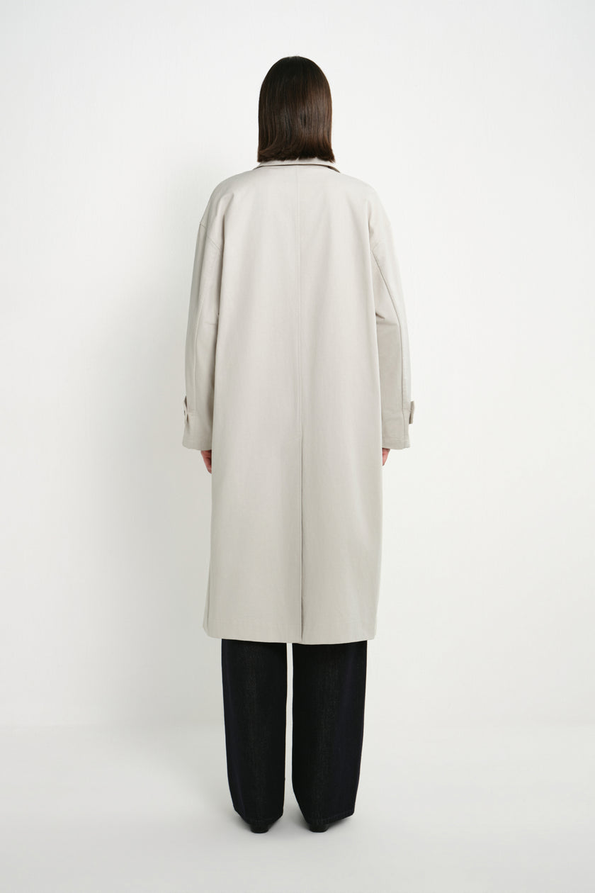 Back view of a model wearing the Rue Sophie Roche Oversized Jacket in cement, highlighting the dropped shoulders, center-back seam, adjustable cuffs, and clean long silhouette.