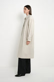 Side view of a model wearing the Rue Sophie Roche Oversized Jacket in cement, featuring a pointed collar, dropped shoulders, adjustable cuff tabs, and a relaxed long-line silhouette.