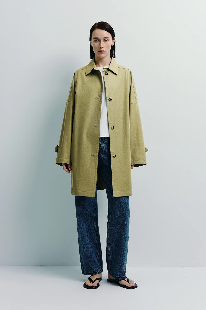 Provenance Oversized Jacket in khaki. Woman wearing a midi-length jacket, denim jeans, and sandals.