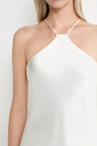 A close-up of a model wearing a white halter-neck camisole top against a plain white background.