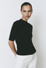 Black Chabot Mock Neck Top with quarter sleeves and relaxed fit, styled with white pants.