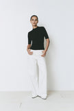 Chabot Mock Neck Top in black with white trousers, relaxed fit.