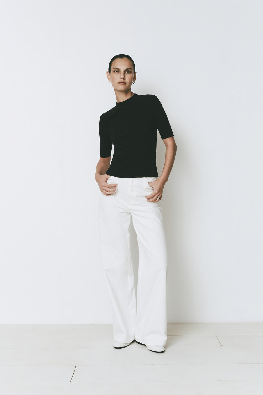 Chabot Mock Neck Top in black with white trousers, relaxed fit.