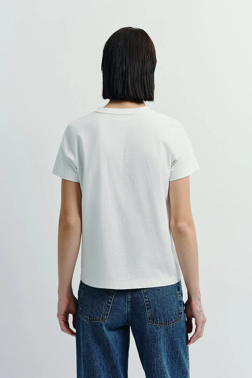 White crew neck tee made of sustainable cotton on woman, paired with denim jeans, minimalist design
