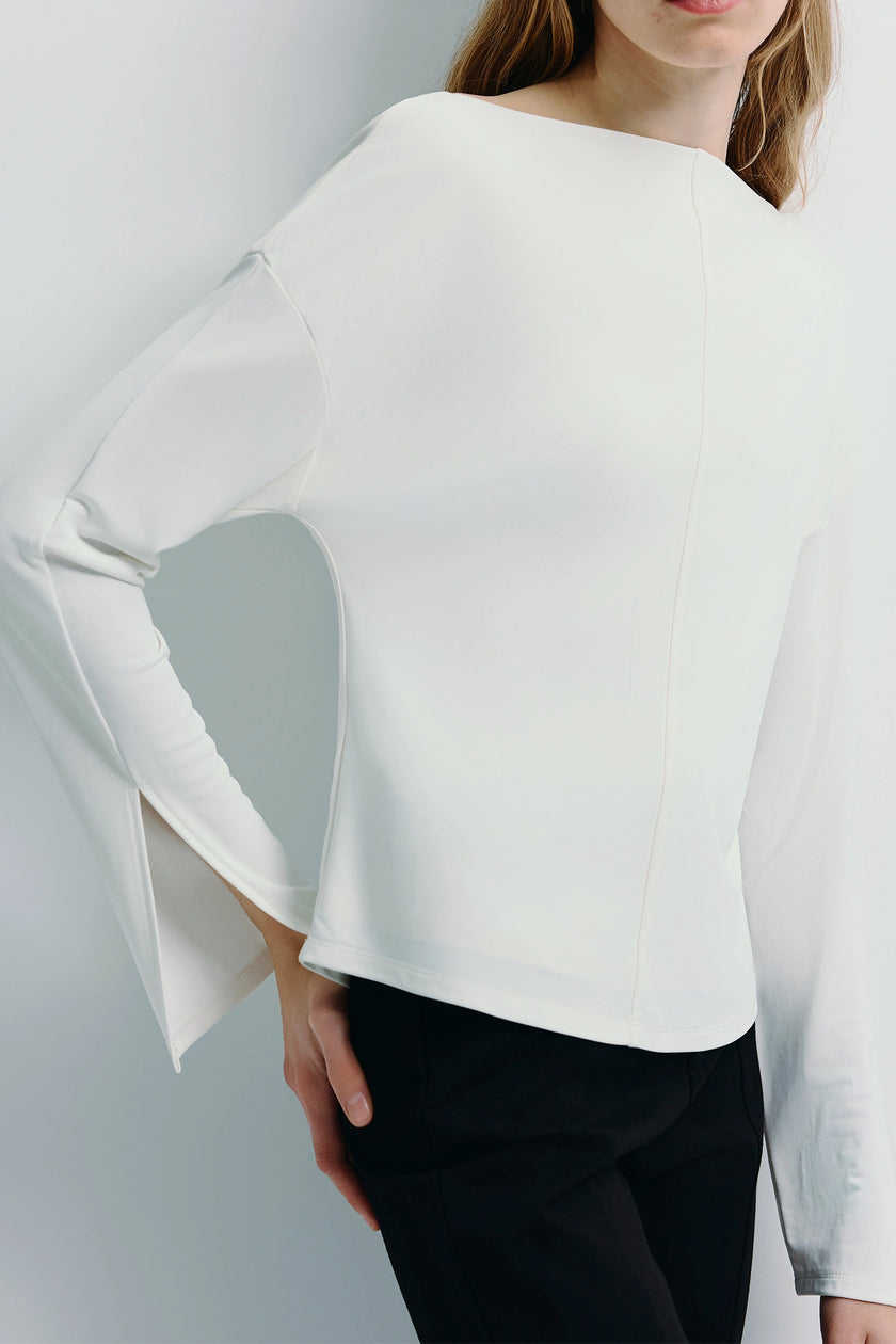 White Laure Top with slit sleeves, paired with black pants, minimalist design, chic style