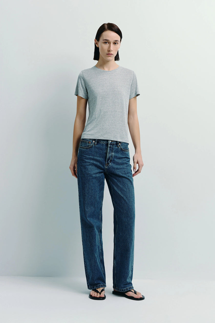 Woman wearing Dan Crew Neck Tee in heather grey, sustainable cotton, paired with blue jeans, for everyday wear.
