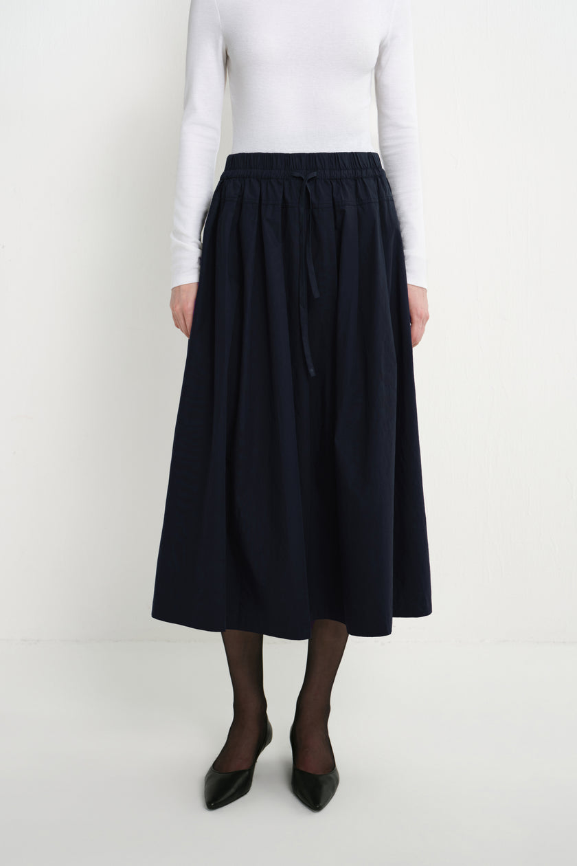Front close-up of the Rue Sophie Panier Drawstring Waist Pleated Skirt in Navy, highlighting the drawstring waistband and softly gathered volume.
