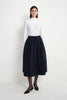 Front view of a model wearing the Rue Sophie Panier Drawstring Waist Pleated Skirt in Navy, highlighting the drawstring waist and full midi silhouette.