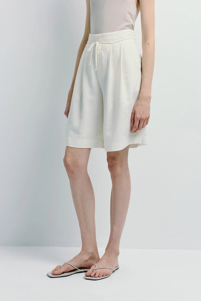 White linen Arc Tie Waist Short on model, tailored fit, warm weather essential.