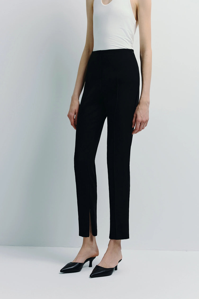Slim-fit Reims Zip Hem Pant in black with zip detail, paired with mules; a modern and sophisticated style.