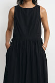 A sleeveless black dress with a round neckline, gathered waist, side drawstrings, and side pockets, shown on a model against a light gray background.