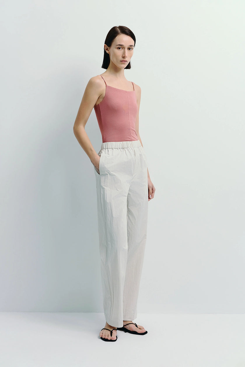 Model wearing light grey crinkled cotton pants, elastic waistband, paired with pink top, relaxed wear.