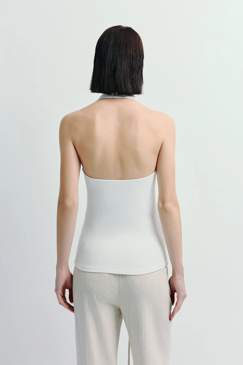 Back view of Chaleur Halter Top in white, paired with beige linen pants, showcasing minimalist design and sculpted fit.