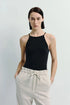 Model wearing Lola Halter Cami Top in black, paired with neutral linen pants, showcasing minimalist design.