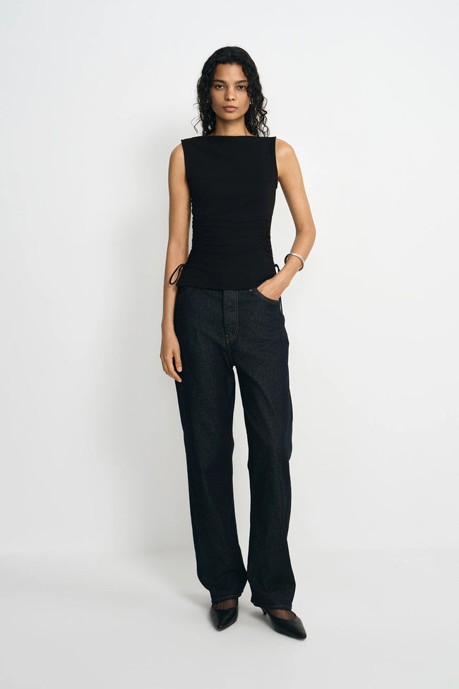 Woman wearing a black sleeveless top and black pants on a white background