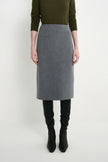 A model wearing a gray wool-blend pencil skirt, styled with an olive green long-sleeve top, black leggings, and black ankle boots, photographed against a light gray studio background.