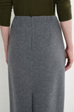 A close-up of a person wearing a high-waisted, knee-length gray wool skirt with a front zipper, paired with an olive green ribbed knit top.