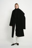 A model wearing the Rue Sophie Grand Scarf Coat in black with an oversized scarf draped over the shoulders, long sleeves, and a relaxed midi silhouette, full-length front view.
