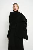 Close-up of the Rue Sophie Grand Scarf Coat in black, highlighting the oversized draped scarf panel, belted waist, and clean structured construction.