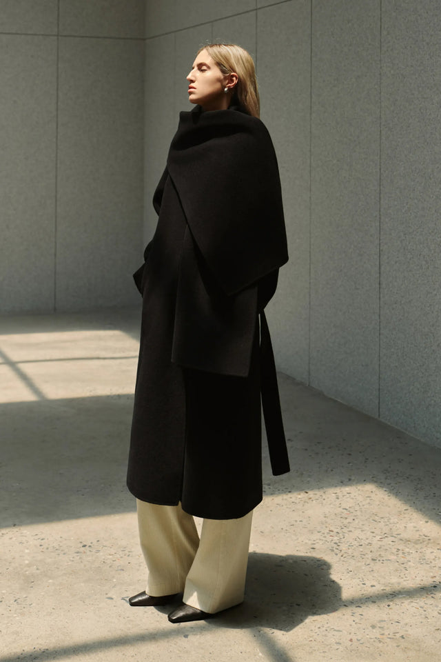 Rue Sophie Grand Scarf Handmade Coat in Black, side view showing the oversized draped scarf collar, belted waist and longline shape.