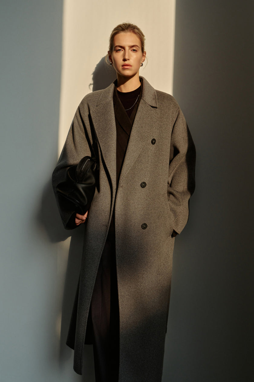 A model wearing the Rue Sophie Martine Belted Coat in grey with wide lapels, button-front detailing, long sleeves, and an oversized tailored silhouette, front view.