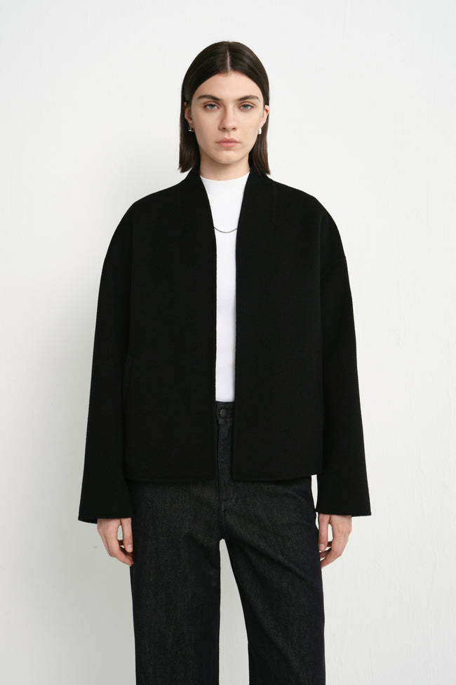 Close-up of the Rue Sophie black cropped jacket highlighting the soft collarless neckline, relaxed shoulder construction, and clean tailored finish.