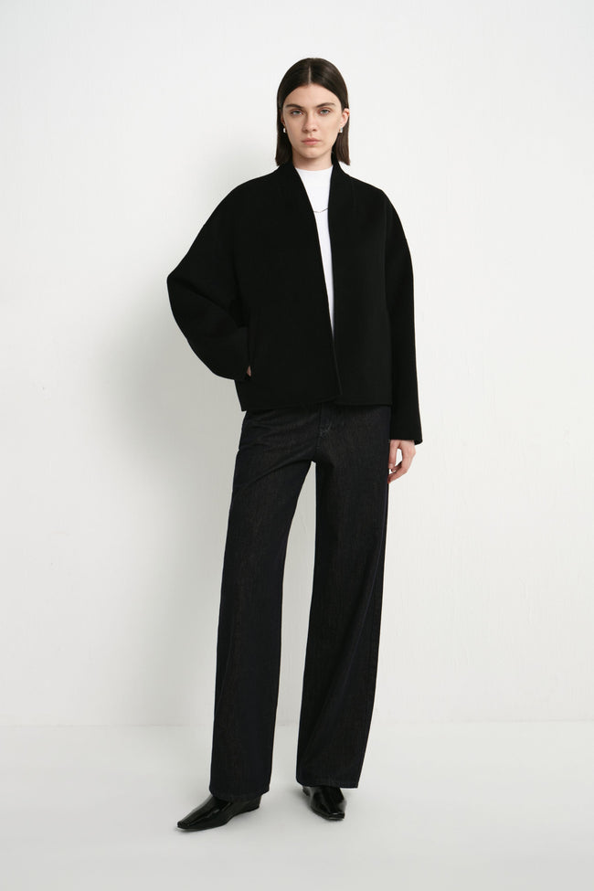 A model wearing the Rue Sophie black cropped jacket featuring a relaxed boxy silhouette, long sleeves, and a clean open-front design, front view.