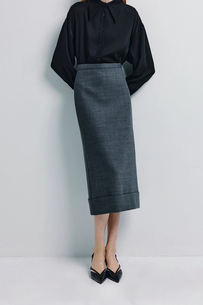 Ruesophie Paley wool-blend midi skirt. Woman in gray A-line skirt and black shirt.