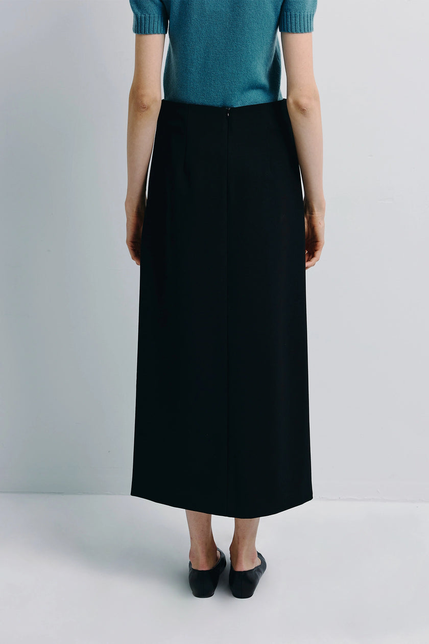 Back view of a woman in a black Bex Open Side Midi Skirt, paired with a teal sweater, showcasing the tailored fit.