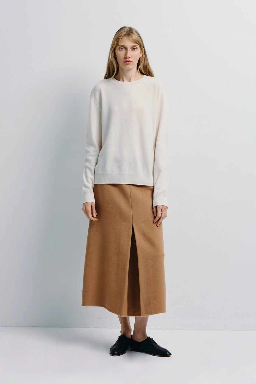 Woman wearing Ambre Pleat Front Midi Skirt, white sweater and black shoes, Rue Sophie