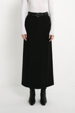 A model wearing the Rue Sophie Camberly Midi Skirt in black with a high waist, belt loops, center-front seam, and long structured silhouette, front view.