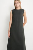 A woman modeling a sleeveless, dark charcoal gray midi dress against a plain light gray studio background.