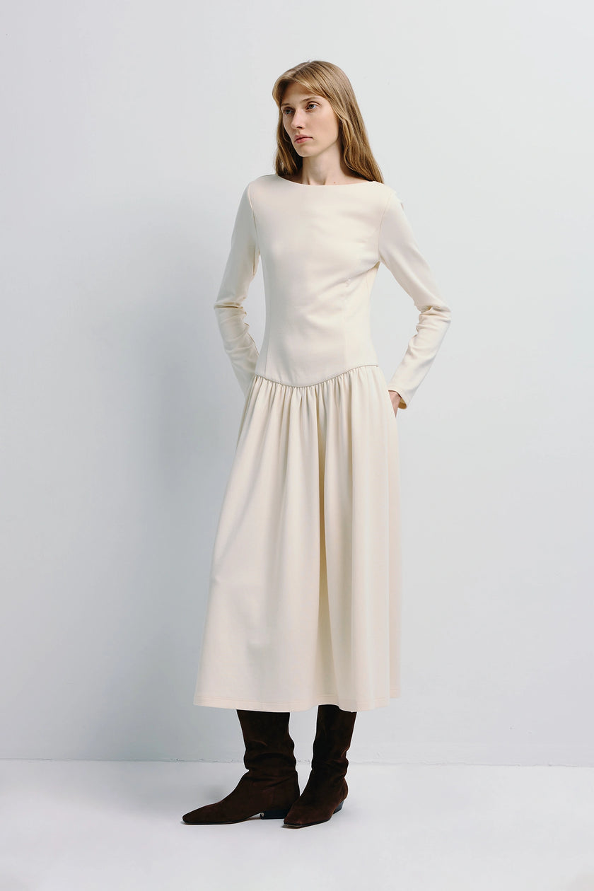 Lisette Boatneck Midi Dress in cream with long sleeves, styled with brown boots, embodying understated elegance.