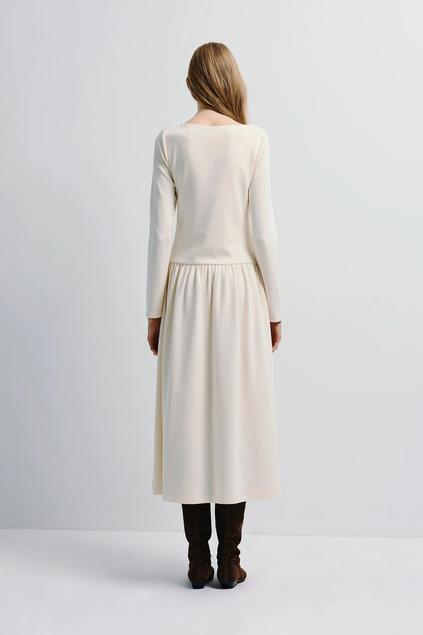 Lisette Boatneck Midi Dress in cream, long sleeves, and flowing skirt. Styled with brown suede boots.
