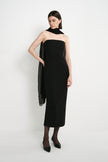 A model wearing the Rue Sophie Webster Tube Dress in black with a straight strapless neckline and fitted column silhouette, styled with a sheer black scarf, three-quarter front view.