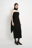 A model wearing the Rue Sophie Webster Tube Dress in black, featuring a strapless neckline, sculpted waist, and streamlined column shape, styled with a sheer black scarf.