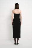 Back view of a model wearing the Rue Sophie Webster Tube Dress in black, highlighting the strapless silhouette, shaping seams, center-back zipper, and straight mid-calf hem.