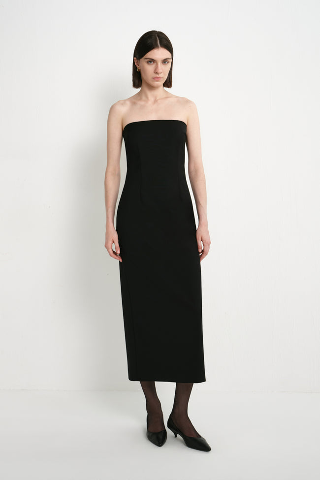 A model wearing the Rue Sophie Webster Tube Dress in black, featuring a strapless straight neckline, fitted column silhouette, and clean mid-calf length, front view.