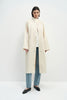A model wearing the Rue Sophie Anne Satin Coat in crème, featuring a high stand collar, metallic snap-front closure, raglan sleeves, side pockets, and a relaxed longline silhouette, front view.