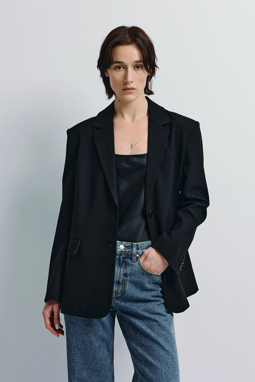 Woman in black Walker Oversized Blazer, black top, and denim jeans