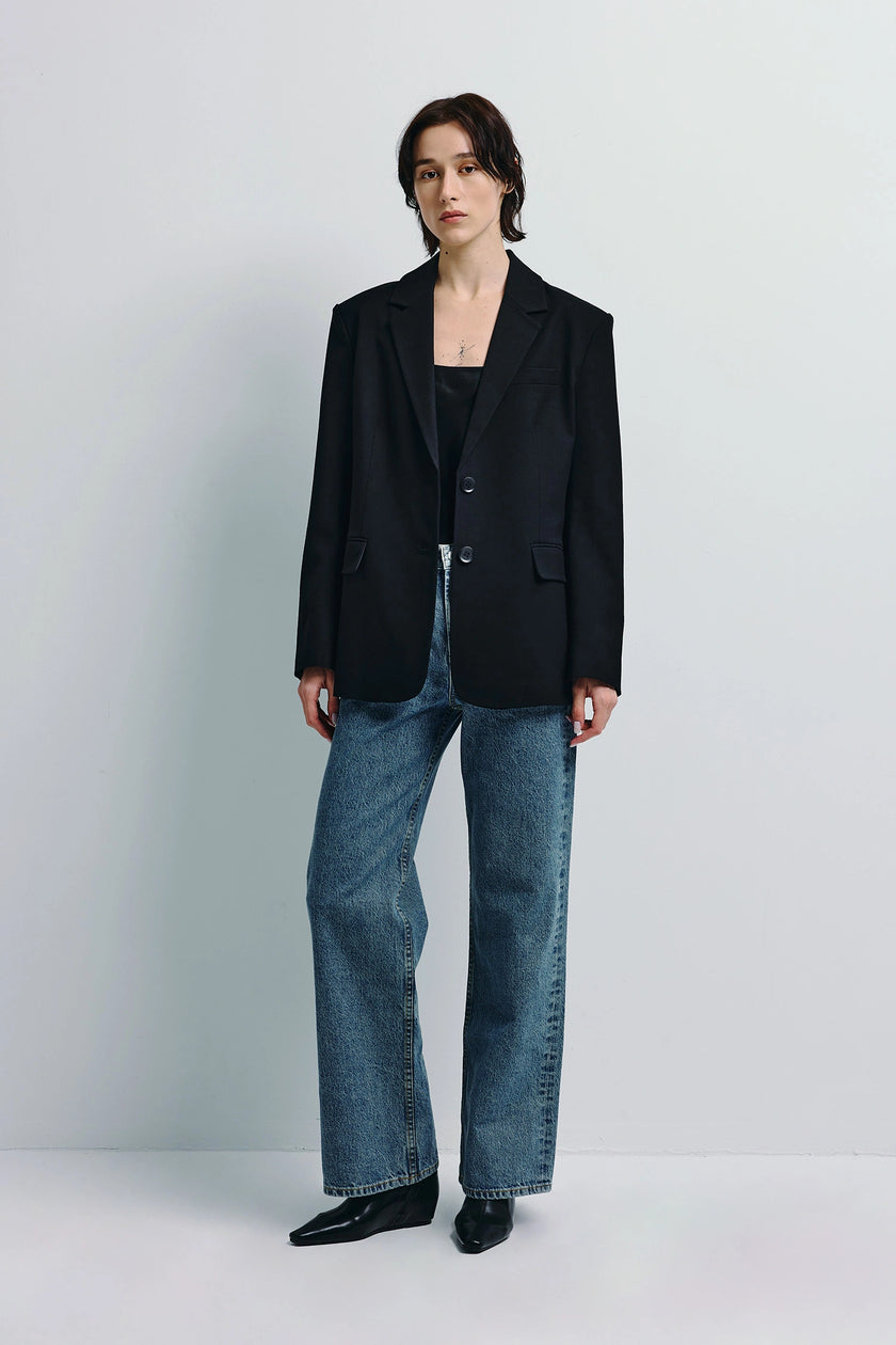 Walker Oversized Blazer in Black worn with jeans. Two-button front, minimal shaping, crisp tailoring.