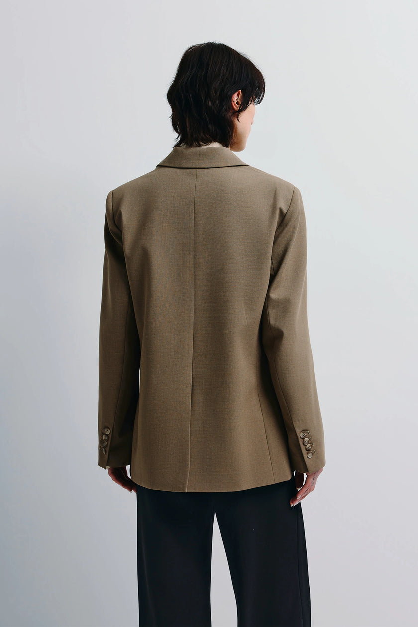 Walker Oversized Blazer in brown, featuring tailored structure and flap pockets. Model wearing black trousers.