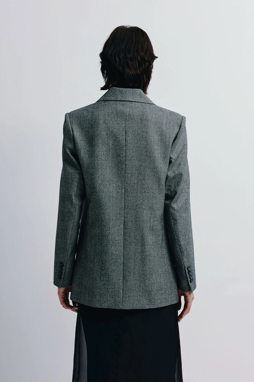 Emery Plaid Blazer in grey plaid wool. Double-breasted with strong shoulders and clean lines, paired with a black skirt.