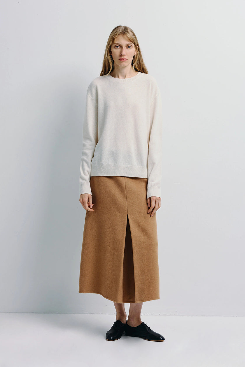 Mia Crewneck Sweater in white, pure wool, paired with tan skirt and black shoes, minimalist design