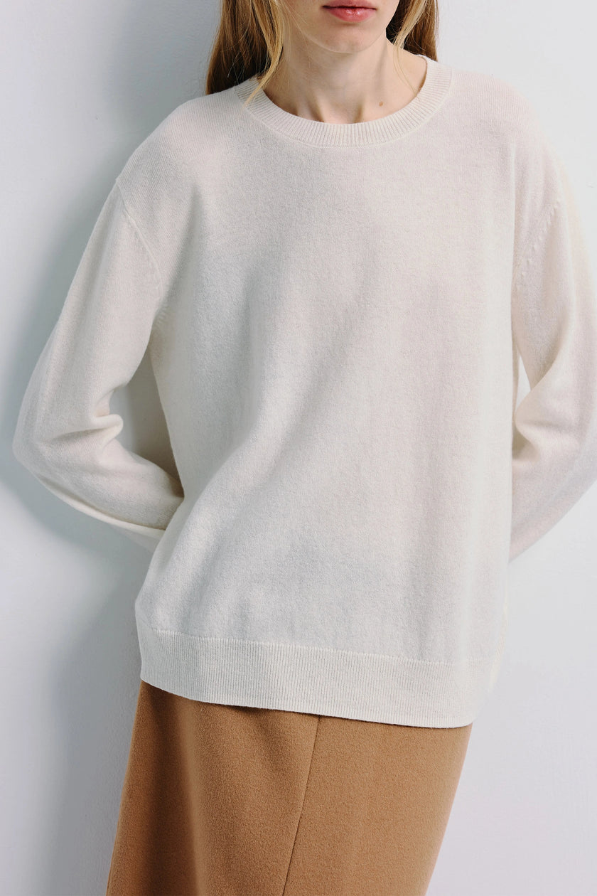 Mia Crewneck Sweater in white, pure wool, minimalist design, woman wearing tan skirt