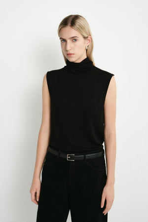 A model wearing a Rue Sophie black sleeveless mock-neck top with a clean straight silhouette and softly draped neckline, front view.